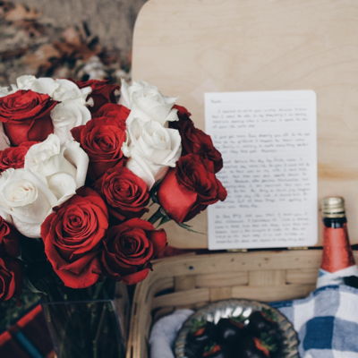 cestino da picnic con mazzo di rose bottiglia di vino e lettera